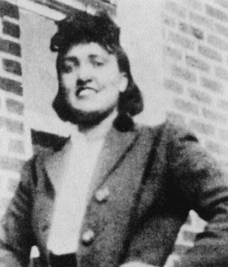 Henrietta Lacks standing beside a brick wall, circa 1945